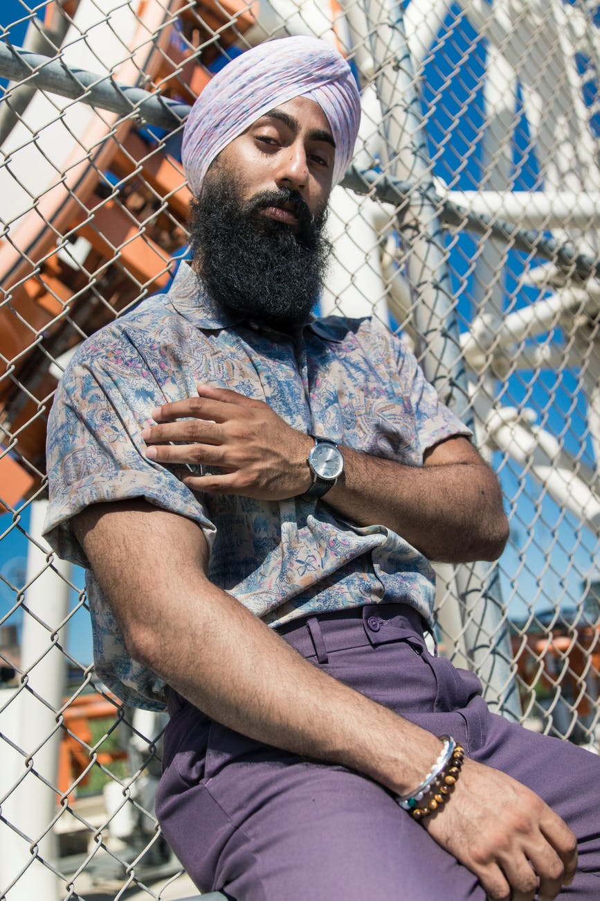 Sikh man wearing mauve pants and a tucked button down with cuffed sleeves.