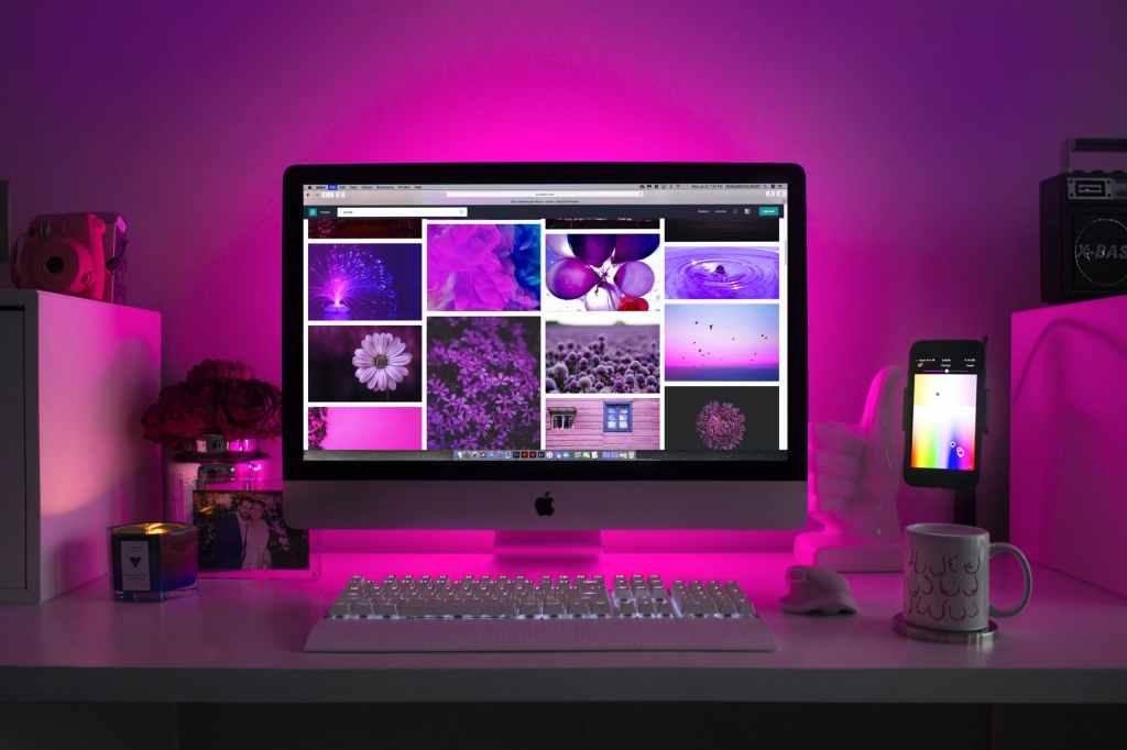 A computer with pink images and a boob mug to the right.